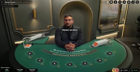 Table de blackjack en direct avec un croupier qui invite à prendre une place